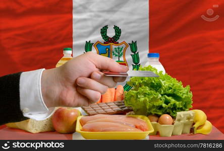 man stretching out credit card to buy food in front of complete wavy national flag of peru