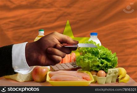 man stretching out credit card to buy food in front of complete wavy national flag of vietnam