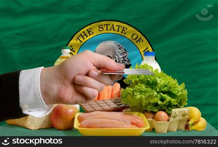 man stretching out credit card to buy food in front of complete wavy american state flag of washington