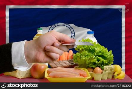 man stretching out credit card to buy food in front of complete wavy american state flag of wyoming