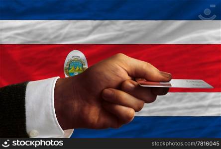 man stretching out credit card to buy goods in front of complete wavy national flag of costa rica