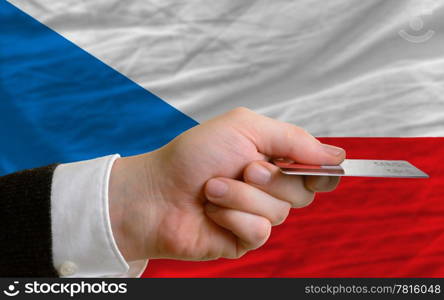 man stretching out credit card to buy goods in front of complete wavy national flag of czech