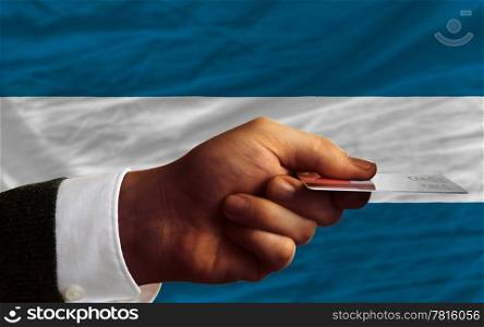 man stretching out credit card to buy goods in front of complete wavy national flag of el salvador