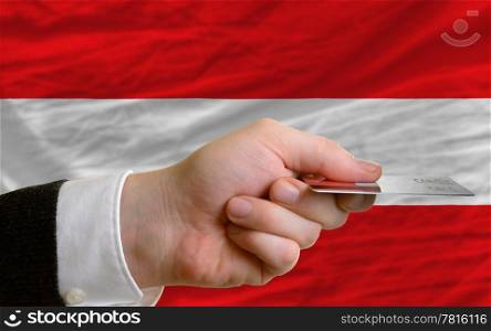 man stretching out credit card to buy goods in front of complete wavy national flag of austria