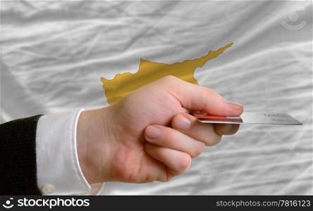 man stretching out credit card to buy goods in front of complete wavy national flag of cyprus