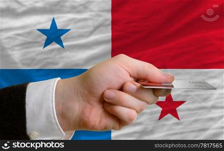 man stretching out credit card to buy goods in front of complete wavy national flag of panama