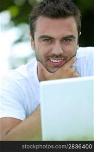 Man stroking his chin and looking at his laptop