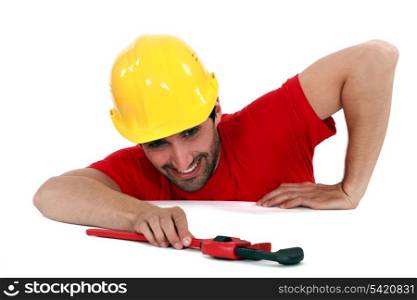 Man struggling to reach a pipe wrench
