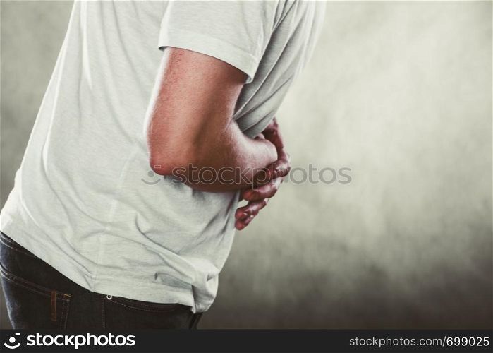 Man suffering from stomach ache abdominal pain. Guy in studio on black.. Man suffering from stomach ache abdominal pain.