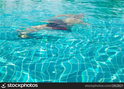 Man swimming underwater in swimming pool