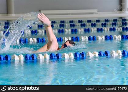 man swims using the crawl stroke in indoor pool