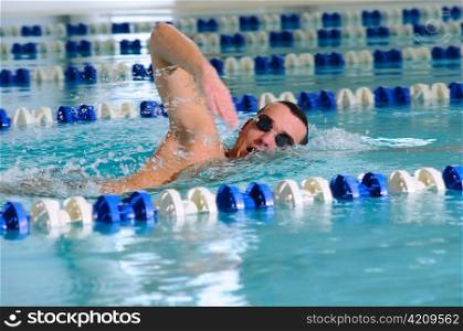 man swims using the crawl stroke in indoor pool