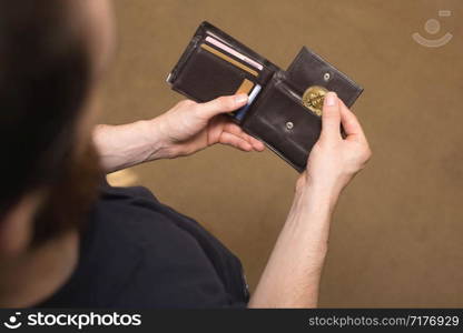 Man takes golden bitcoin out of his wallet, Virtual currency. Crypto currency. New virtual money. businessman Opened wallet. close-up. Man takes golden bitcoin out of his wallet, Virtual currency. Crypto currency. New virtual money. businessman Opened wallet.