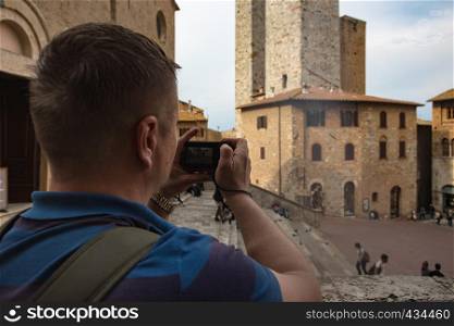 man taking a photo of central square of San Gimignano Tuscany Italy