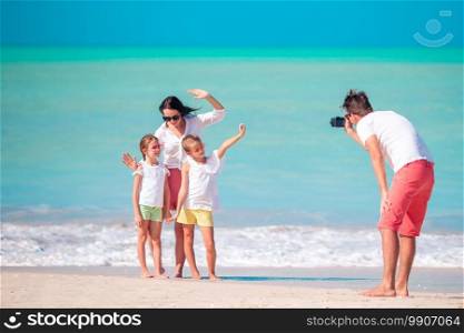 Man taking a photo of his family. Family of four taking a selfie photo on their beach holidays. Family beach vacation