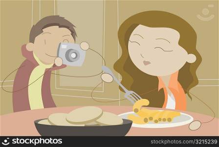 Man taking a photograph of a young woman eating food