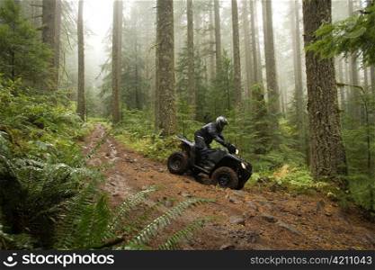 Man Taking ATV down Steep Forest Hill