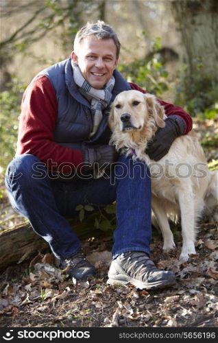 Man Taking Dog On Walk Through Autumn Woods