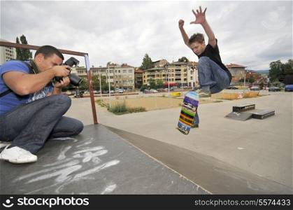 Man taking photo of boy skating in park