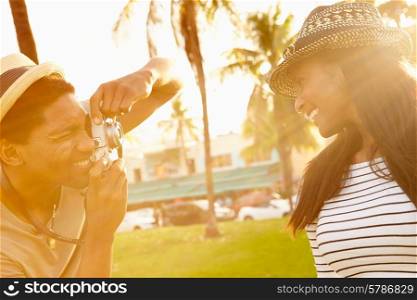 Man Taking Photograph Of Woman In Park