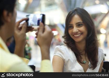 Man taking photos of beautiful woman at shopping mall