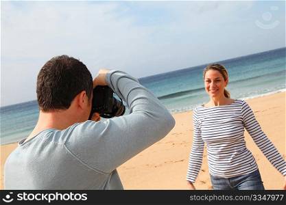 Man taking picture of girlfriend at the beach
