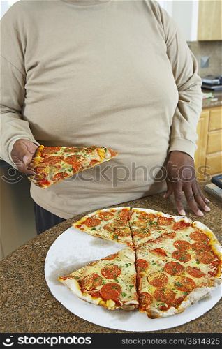 Man taking slice of pizza from kitchen counter