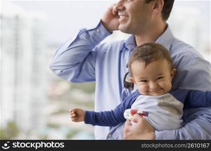 Man talking on a mobile phone and holding his son