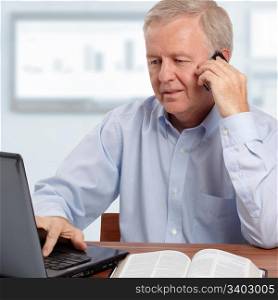 Man talking on phone in front of the laptop and the Bible