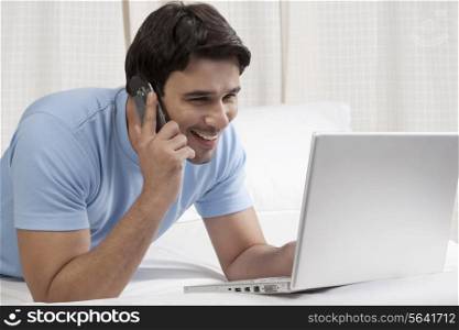 Man talking on the phone while working on a laptop
