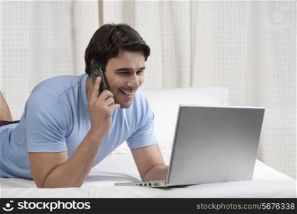 Man talking on the phone while working on a laptop