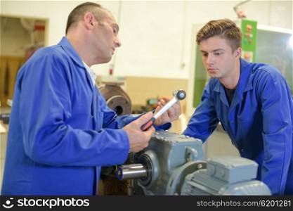 Man talking to apprentice, holding socket wrench