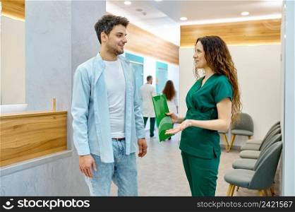 Man talking with doctor in clinic hall. Practitioner explaining good news for male patient. Man talking with doctor in clinic hall