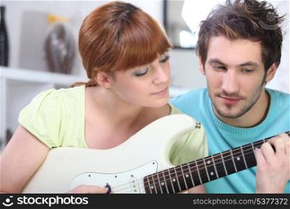 Man teaching a woman to play the guitar