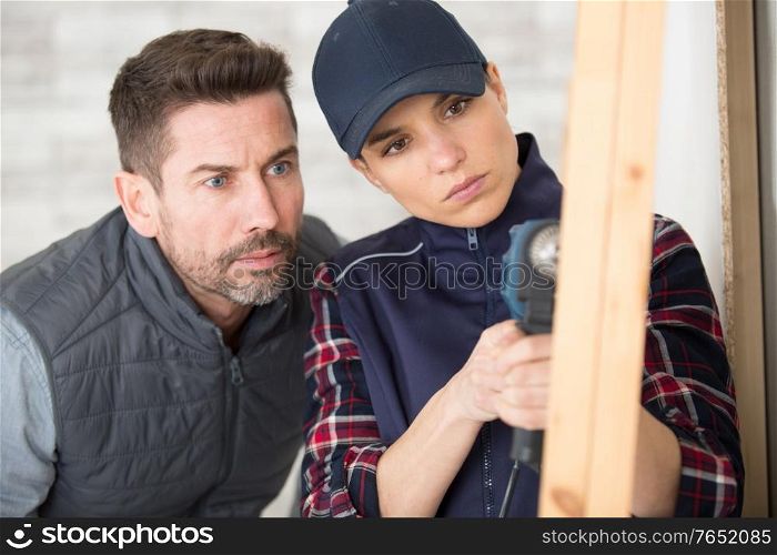 man teaching female worker to drill