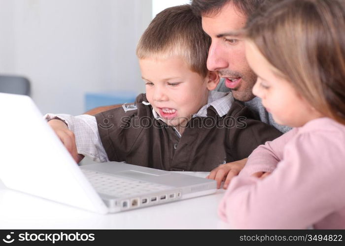 Man teaching kids how to use laptop computer