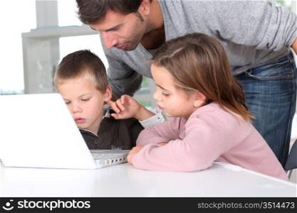 Man teaching kids how to use laptop computer