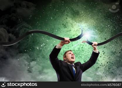 Man tearing cable. Determined businessman tearing electricity cable with hands
