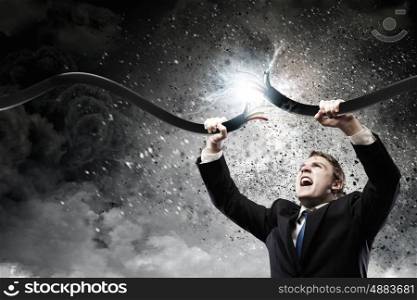 Man tearing cable. Determined businessman tearing electricity cable with hands