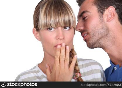 Man telling a secret to a woman
