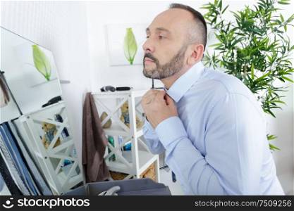 man ties up in front of a mirror in room