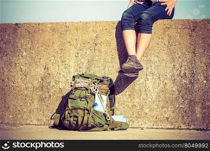 Man tourist backpacker relaxing outdoor sitting on grunge wall. Adventure, summer, tourism active lifestyle. Young guy tramping