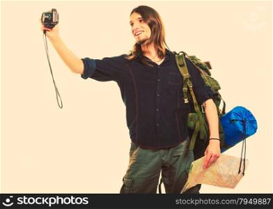 Man tourist backpacker taking photo with camera.. Man tourist backpacker on trip taking photo picture with camera. Young guy hiker backpacking holding map. Summer vacation travel. Instagram filtered.