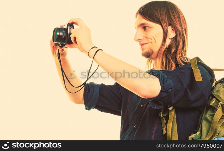 Man tourist backpacker taking photo with camera.. Man tourist backpacker on trip taking photo picture with camera. Young guy hiker backpacking. Summer vacation travel. Instagram filtered.