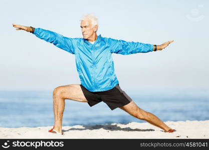 Man training on beach outside. Handsome caucasian male doing exercises on beach