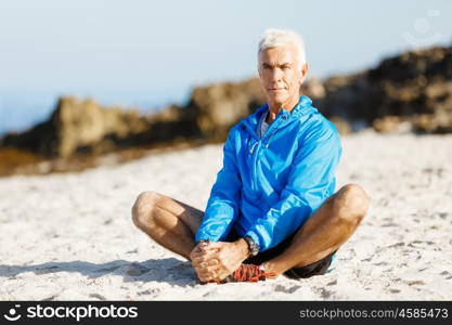 Man training on beach outside. Handsome caucasian male doing exercises on beach