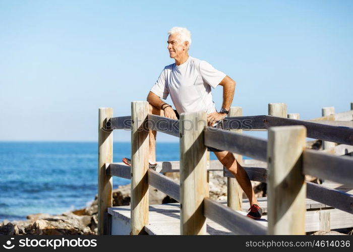 Man training on beach outside. Handsome caucasian male doing exercises on beach