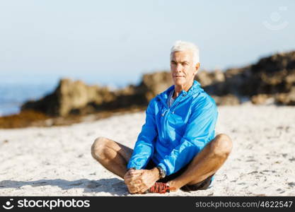 Man training on beach outside. Handsome caucasian male doing exercises on beach