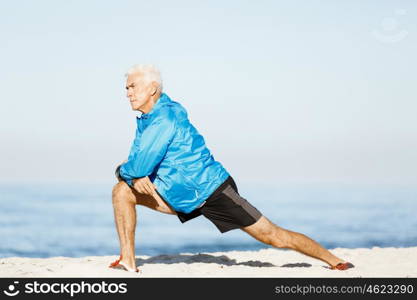 Man training on beach outside. Handsome caucasian male doing exercises on beach