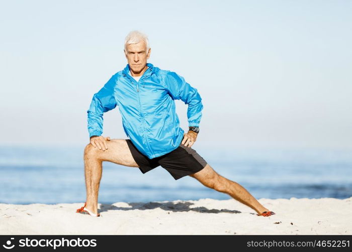 Man training on beach outside. Handsome caucasian male doing exercises on beach